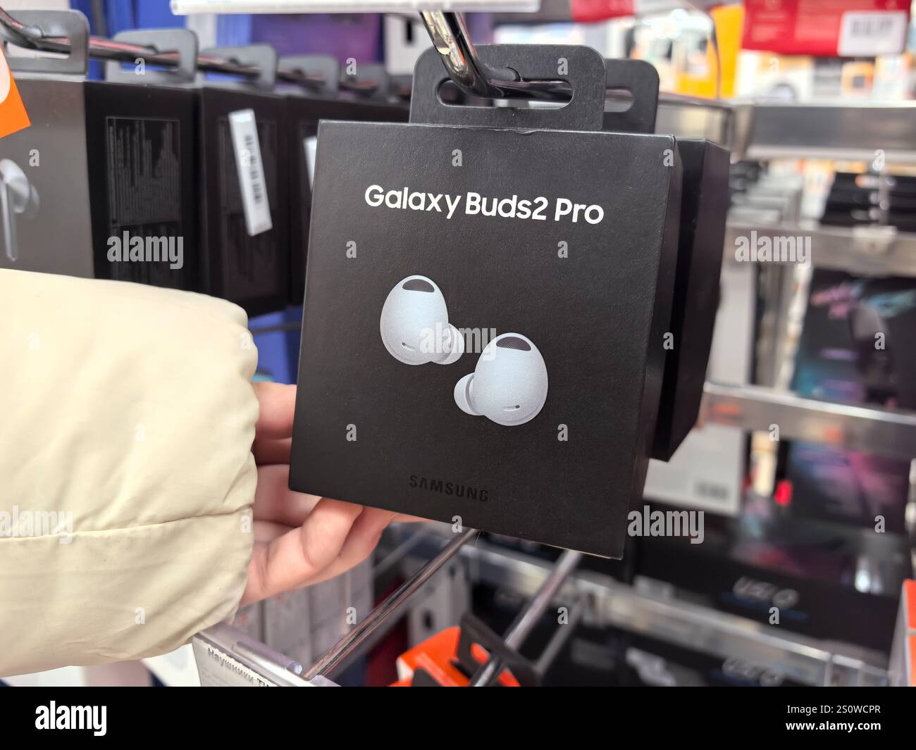 Bobruisk, Biélorussie - 29 décembre 2024 : un coup de main pour un emballage élégant d'écouteurs sans fil dans un magasin d'électronique dynamique. Banque D'Images