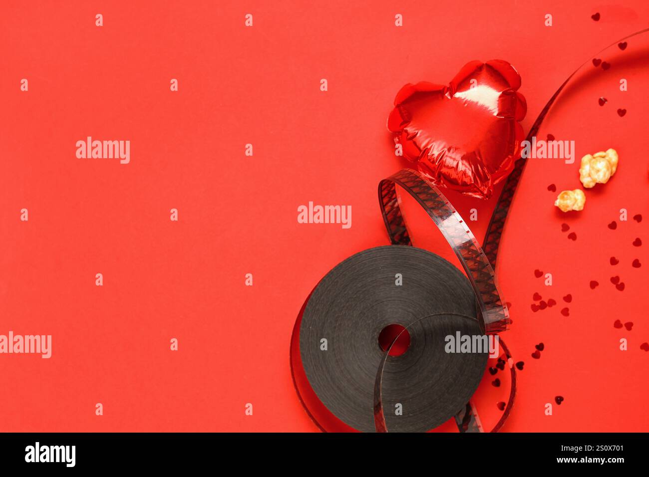 Bobine de film avec pop-corn et ballon d'air en forme de coeur sur fond rouge. Célébration de la Saint-Valentin Banque D'Images