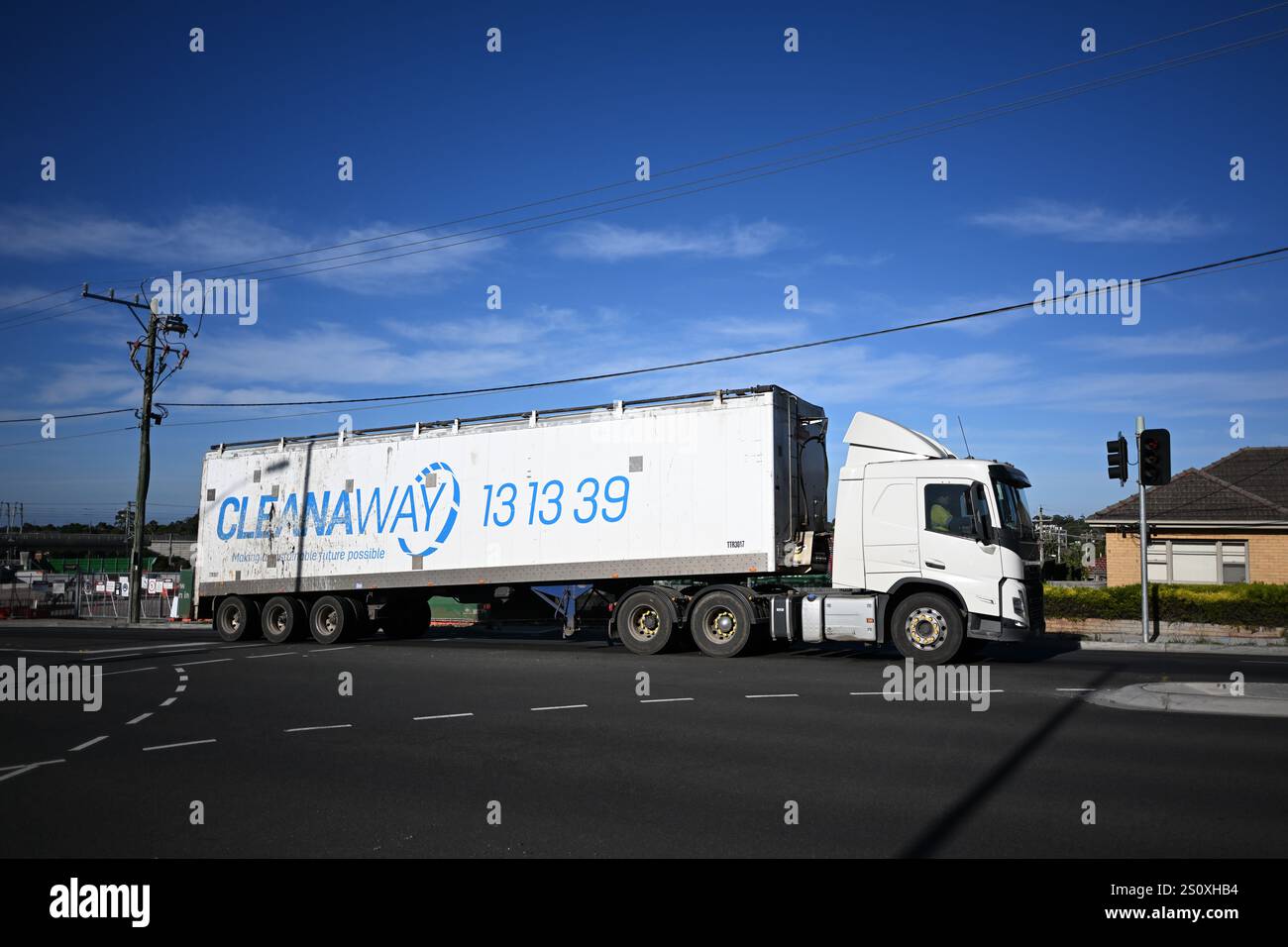 Vue latérale d'un véhicule blanc Cleanaway, un camion semi-remorque Volvo, qui traverse une intersection dans la banlieue de Melbourne Banque D'Images Vue latérale d'un véhicule blanc Cleanaway, un camion semi-remorque Volvo, qui traverse une intersection dans la banlieue de Melbourne Banque D'Images