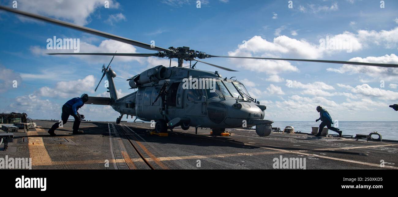 MER DE CHINE MÉRIDIONALE (Dec. 25, 2024) – le matelot de bateau William Davis, de Louis, Moya, et le matelot de bateau Stephan Tande, de Newark, New Jersey, chock et chaîne un MH-60S Sea Hawk affecté aux “Black Knights” de Helicopter Sea combat Squadron (HSC) 4 sur le pont d'envol à bord du destroyer de classe Arleigh Burke USS Sterett (DDG 104), 25 2024. Le Carl Vinson Carrier Strike Group mène actuellement des opérations courantes dans la zone d'opérations de la 7e flotte américaine. (Photo de l'US Navy par Brianna Walker, spécialiste des communications de masse, 3e classe) Banque D'Images