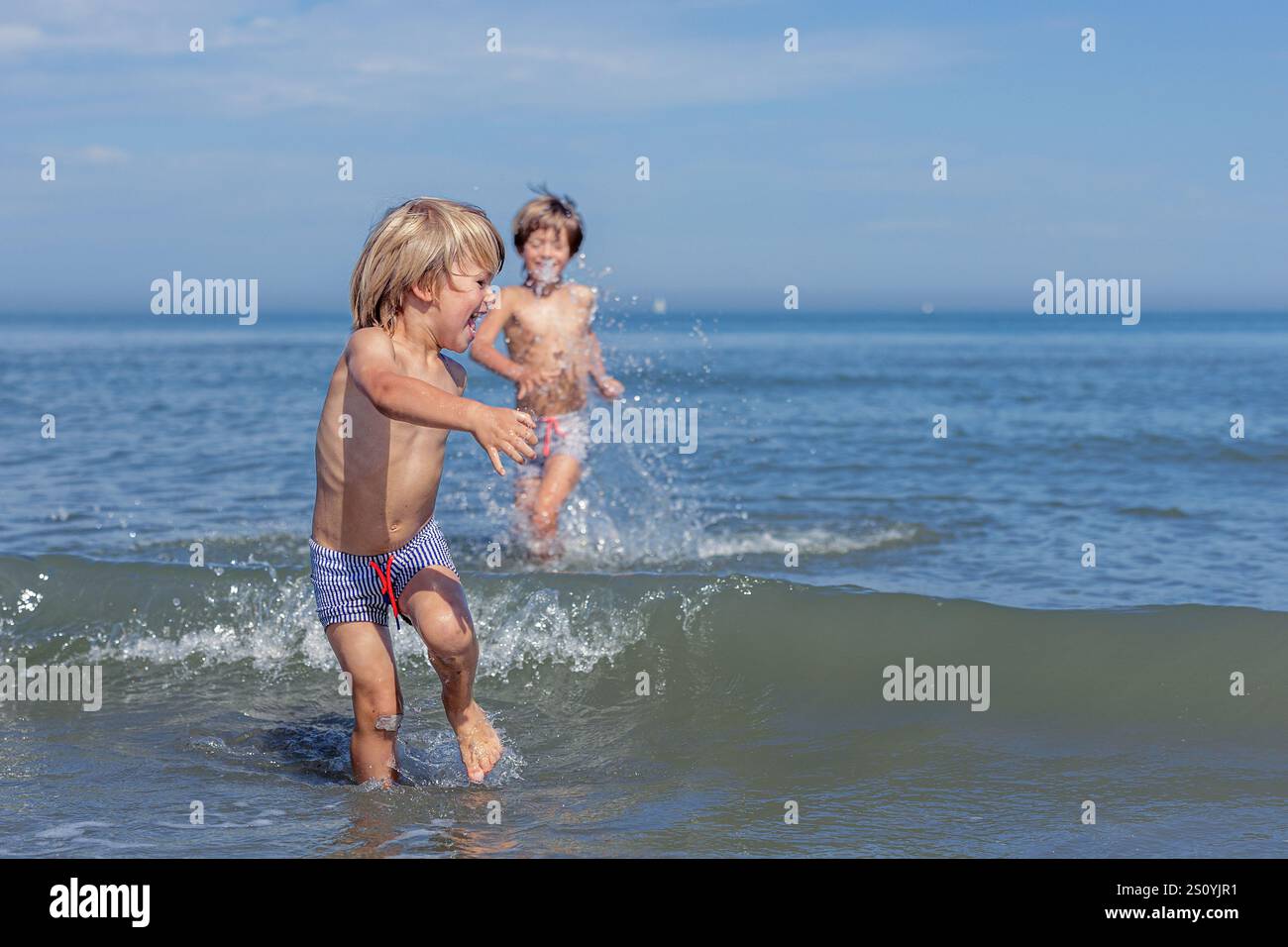 Vagues joyeuses et rire des frères et sœurs à la plage Banque D'Images