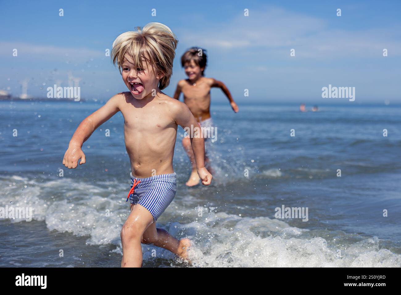 Joyeux sprint : les enfants rient dans Ocean Waves Banque D'Images