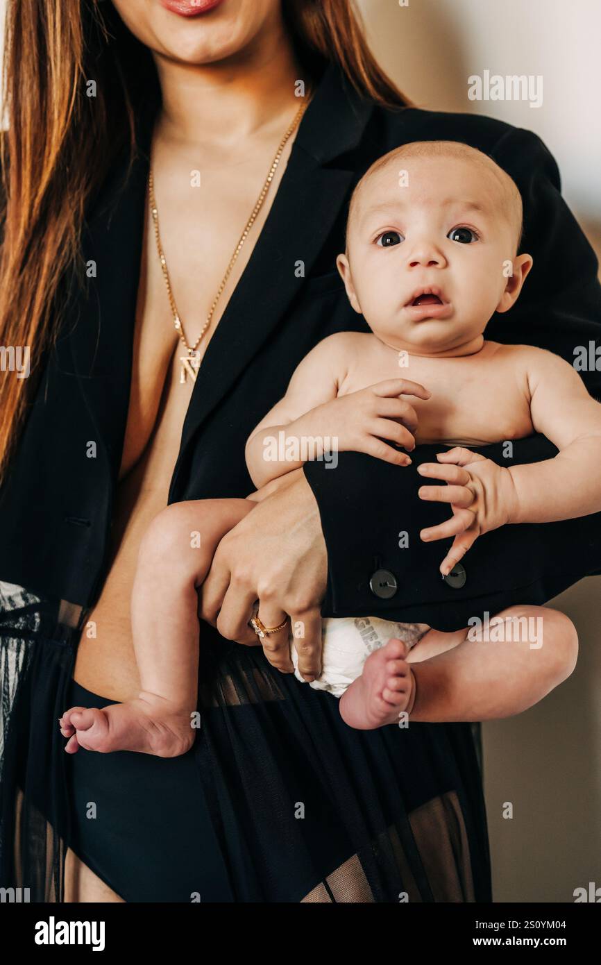 Gros plan d'un bébé tenu par une mère en noir Banque D'Images