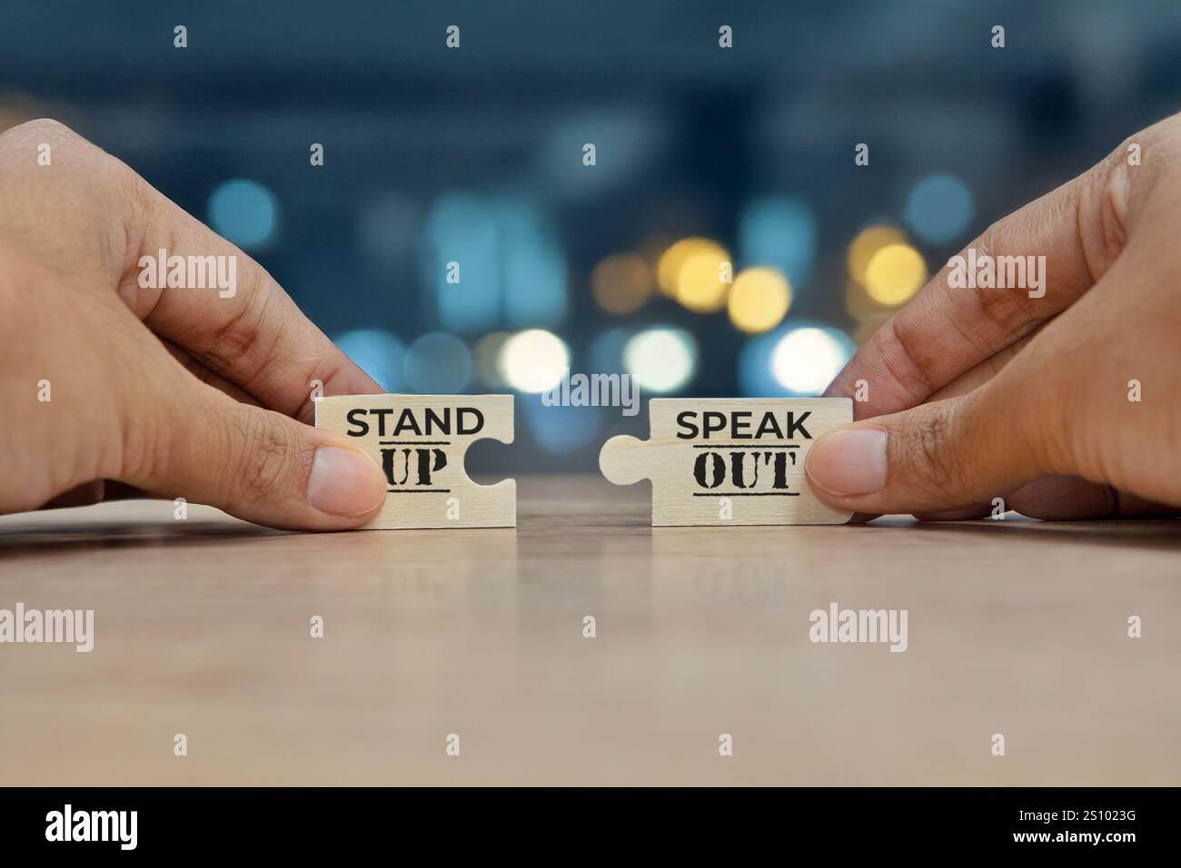 Deux mains tenant deux pièces de puzzle qui s'emboîtent pour former la phrase « debout parler dehors ». L'importance de prendre position et de parler à nouveau Banque D'Images