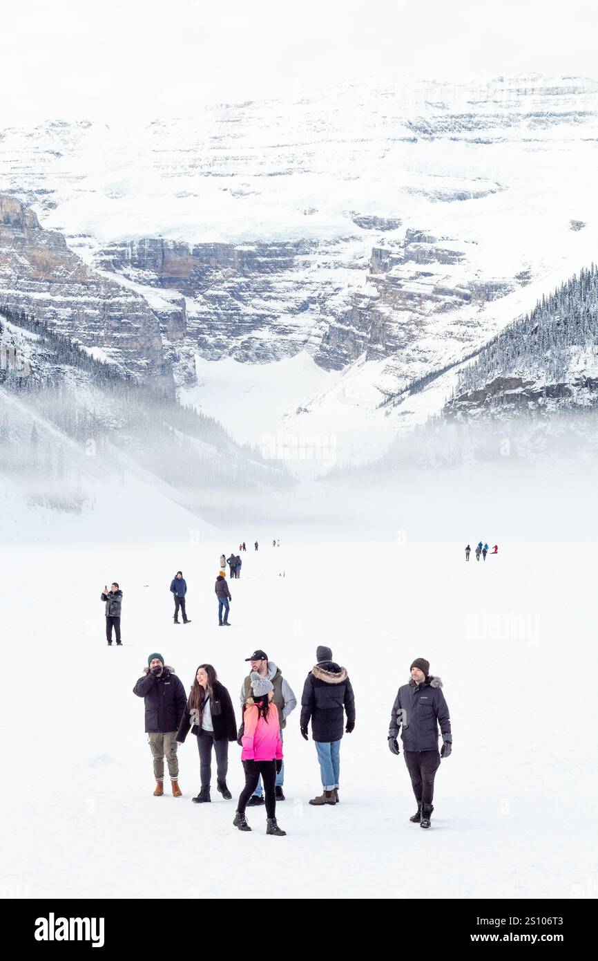 Paysage panoramique du lac Louise gelé avec des visiteurs éclipsés par les montagnes enneigées au parc national Banff, Canada Banque D'Images Paysage panoramique du lac Louise gelé avec des visiteurs éclipsés par les montagnes enneigées au parc national Banff, Canada Banque D'Images