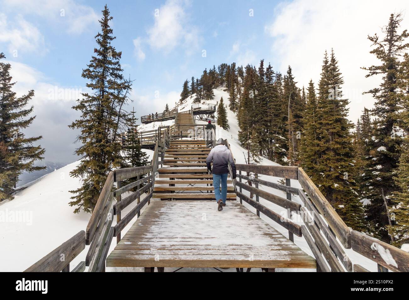 Un touriste en vêtements d'hiver grimpant les escaliers en bois jusqu'à la station des rayons cosmiques de Sulphur Mountain dans le parc national Banff, Alberta, Canada en hiver Banque D'Images Un touriste en vêtements d'hiver grimpant les escaliers en bois jusqu'à la station des rayons cosmiques de Sulphur Mountain dans le parc national Banff, Alberta, Canada en hiver Banque D'Images