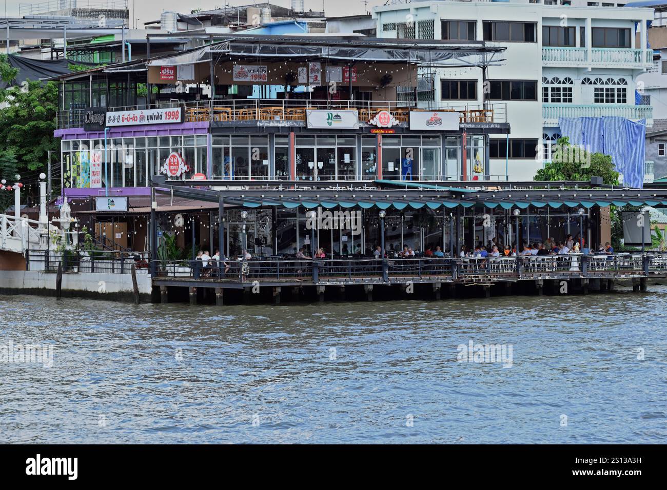 Les touristes occidentaux déjeunent dans un restaurant thaïlandais au bord de la rivière Chao Phraya à Bangkok, en Thaïlande. Banque D'Images