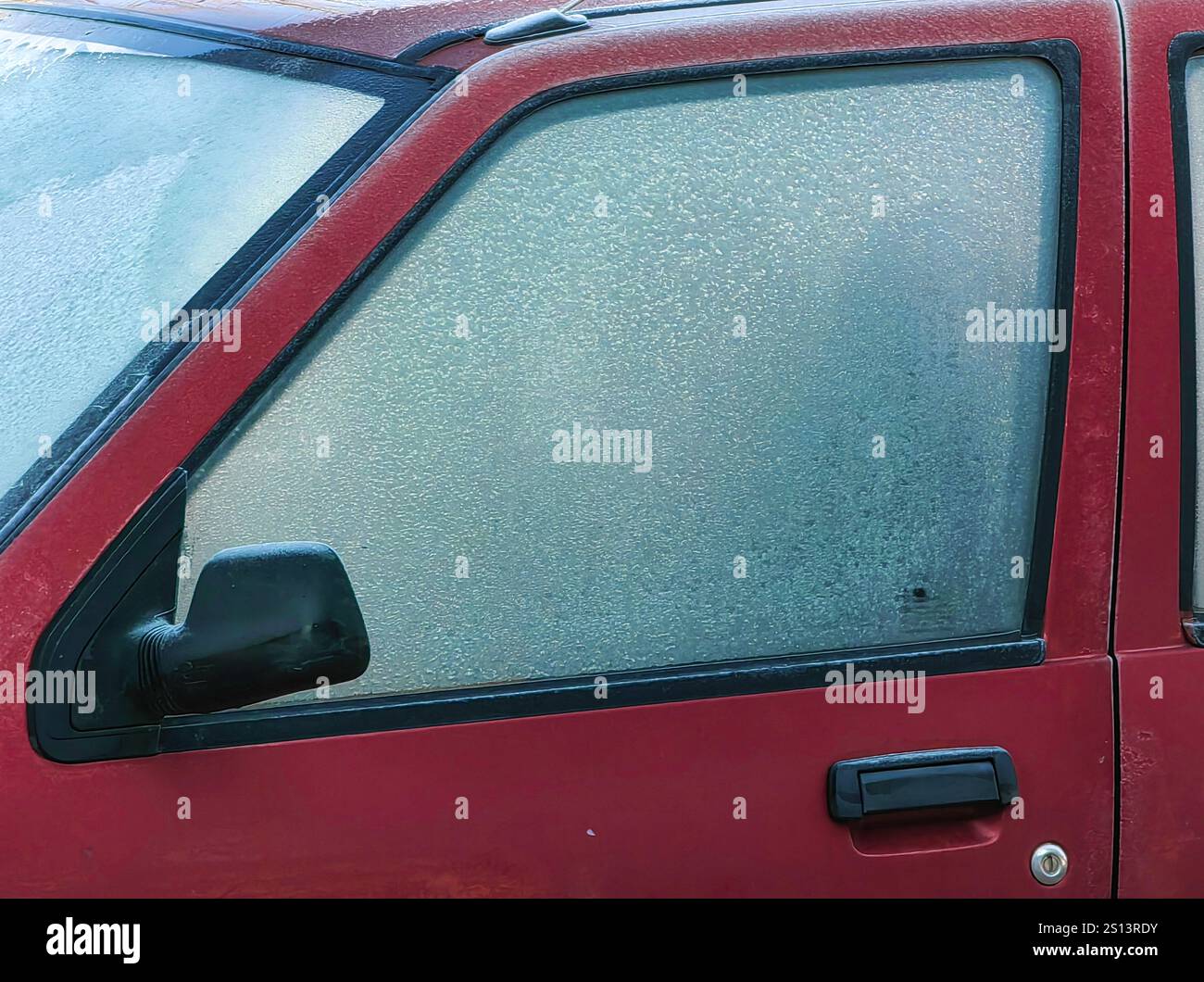 Motifs gelés : verre givré et poignée d'une voiture en stationnement, avec rétroviseur arrière gauche. Banque D'Images