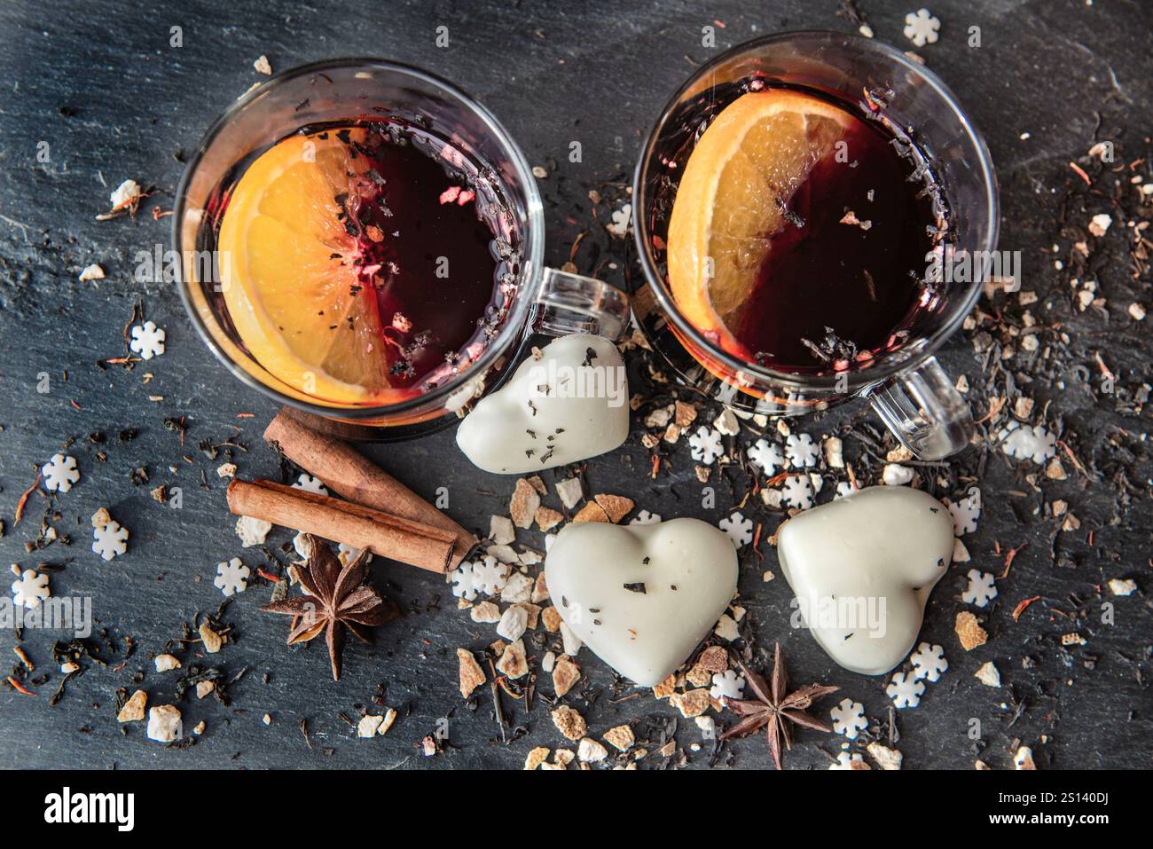 vue de dessus sur tranche d'orange dans du vin chaud dans deux verres avec des biscuits en forme de coeur et des épices disposés sur un fond d'ardoise grise Banque D'Images