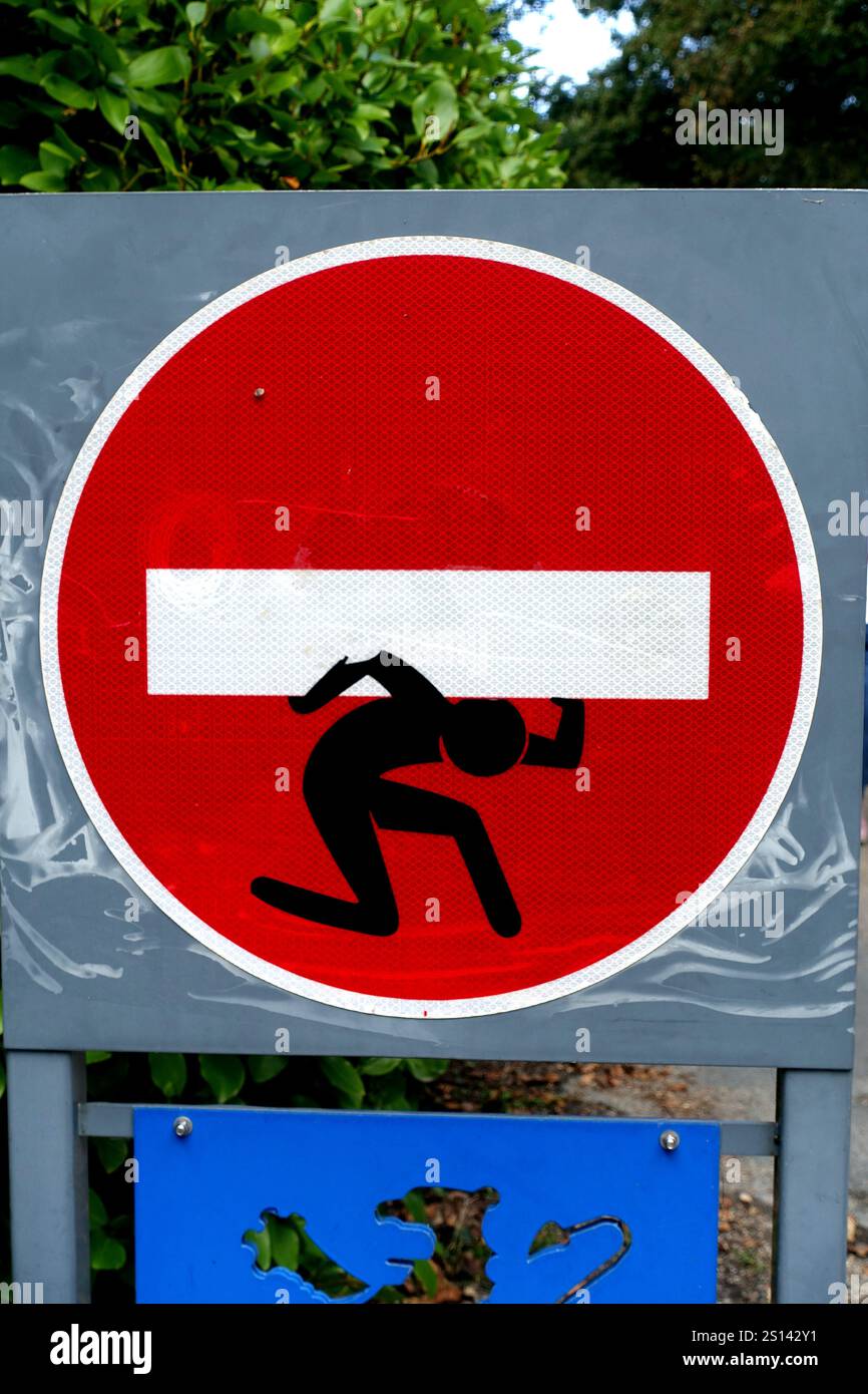 Little Man collé à un panneau « interdiction d’entrée » porte la lourde barre transversale, France, Bretagne, Pont-Croix Banque D'Images