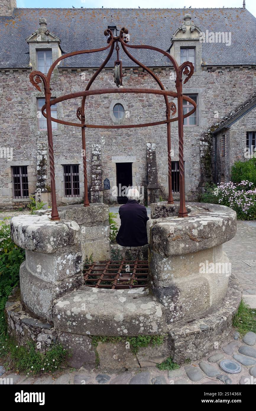 Homme assis sur la vieille fontaine de l’abbaye de Beauport, France, Bretagne, Département des côtes-d’Armor, Paimpol Banque D'Images