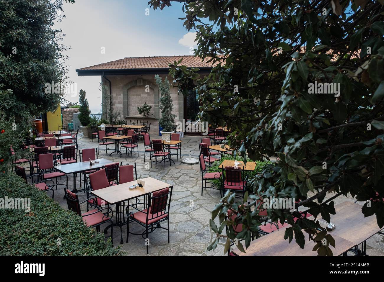 Restaurant avec arbres et plantes à l'extérieur. Restaurant extérieur dans la rue de la ville européenne. Tables et chaises sur la terrasse. Photo de voyage, personne, s Banque D'Images