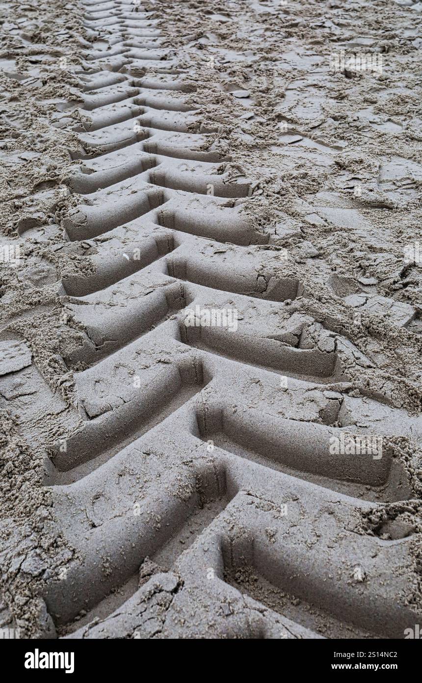 Traces de la bande de roulement d'un camion hors route laissées dans le sable sur la plage. Banque D'Images