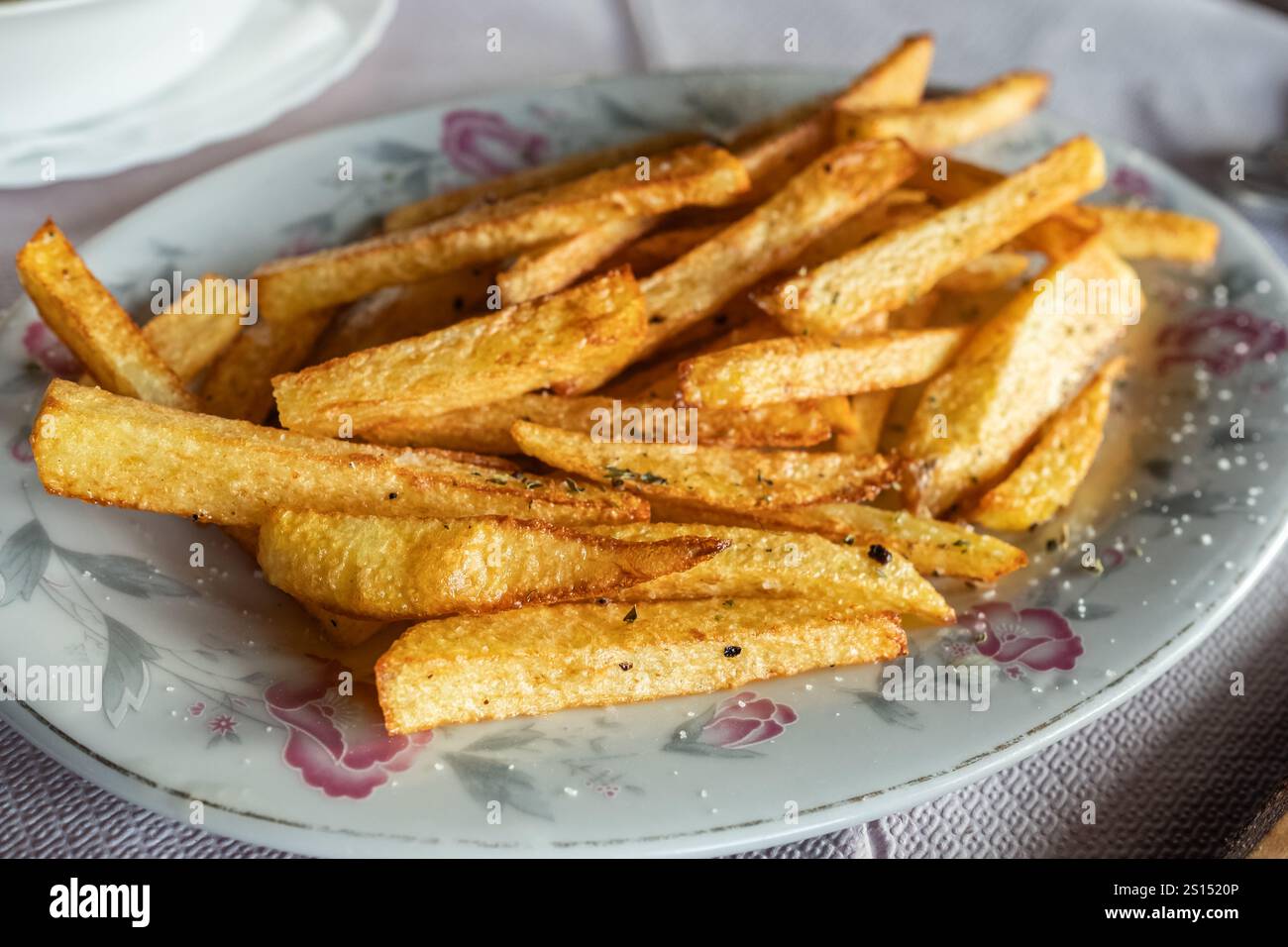 Savoureuses tranches de pommes de terre frites. Frites salées dans une assiette blanche dans un restaurant traditionnel. Des bâtonnets de pommes de terre frites appétissants avec du croustillant doré. H Banque D'Images