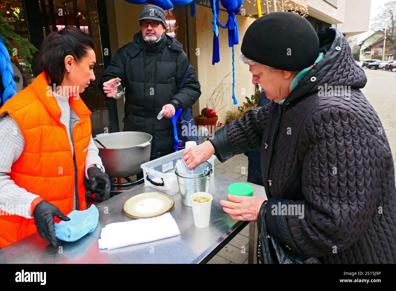 UZHHOROD, URAINE - 30 DÉCEMBRE 2024 - Un volontaire verse des portions de soupe de poisson pour les personnes âgées dans la ligne, Uzhhorod, ouest de l'Ukraine Banque D'Images