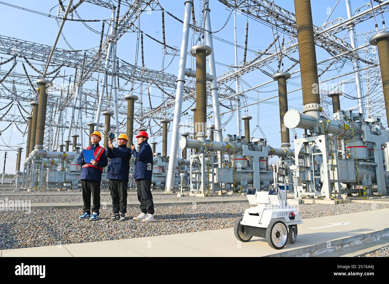 CHUZHOU, CHINE - 1er JANVIER 2025 - Un robot intelligent 5G et du personnel d'exploitation et de maintenance inspectent l'équipement d'alimentation principal en 50 Banque D'Images