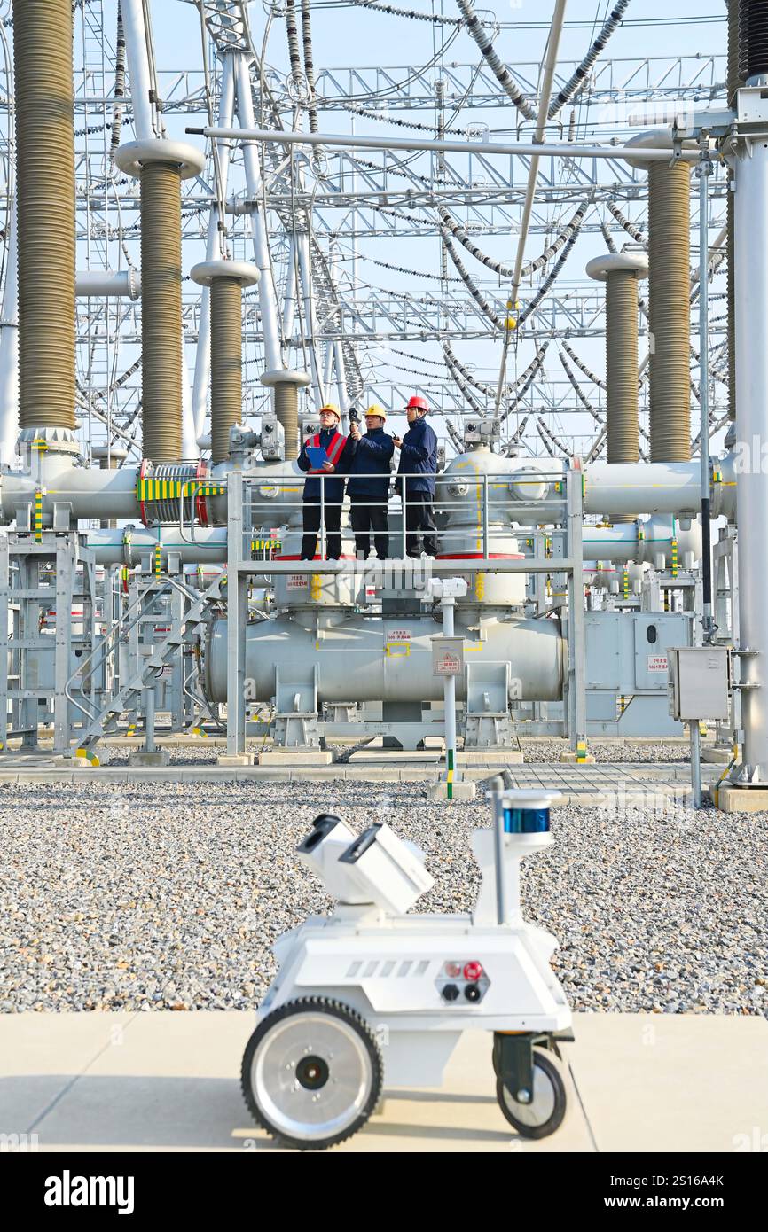 CHUZHOU, CHINE - 1er JANVIER 2025 - Un robot intelligent 5G et du personnel d'exploitation et de maintenance inspectent l'équipement d'alimentation principal en 50 Banque D'Images