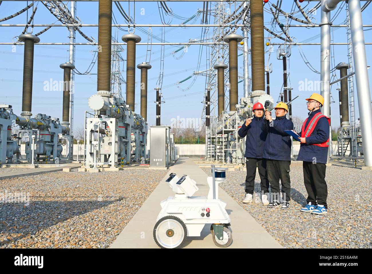 CHUZHOU, CHINE - 1er JANVIER 2025 - Un robot intelligent 5G et du personnel d'exploitation et de maintenance inspectent l'équipement d'alimentation principal en 50 Banque D'Images