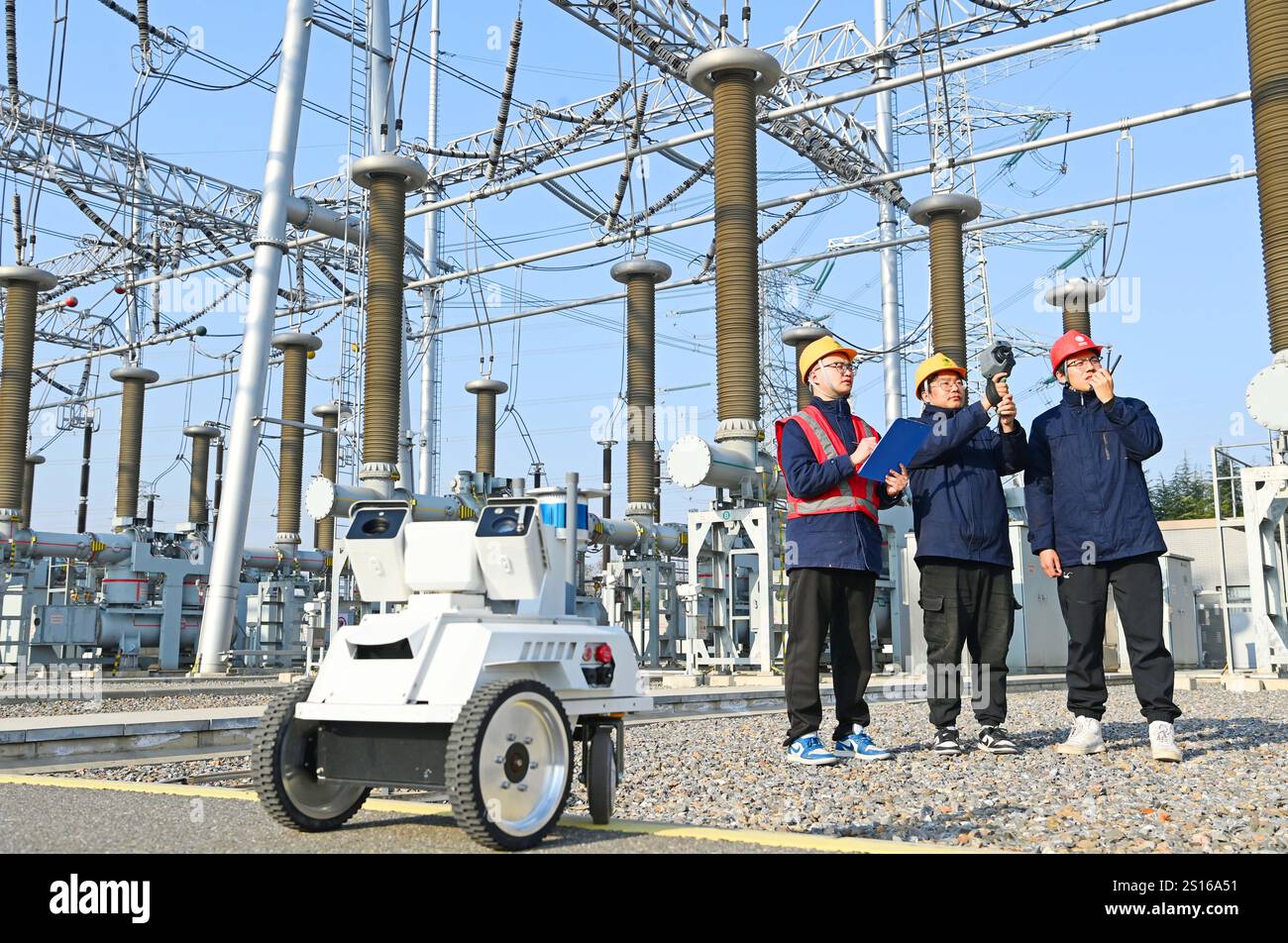 CHUZHOU, CHINE - 1er JANVIER 2025 - Un robot intelligent 5G et du personnel d'exploitation et de maintenance inspectent l'équipement d'alimentation principal en 50 Banque D'Images