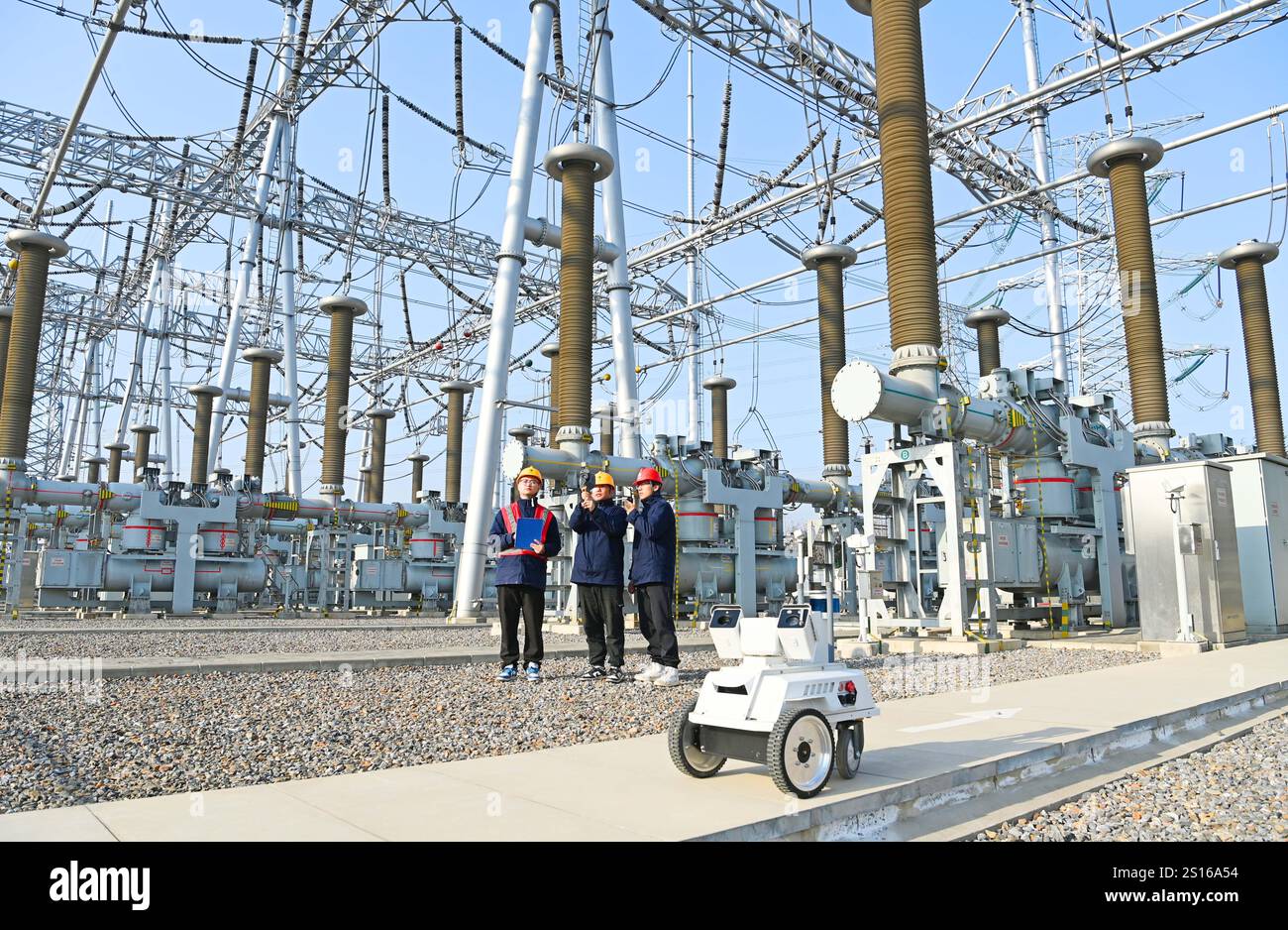 CHUZHOU, CHINE - 1er JANVIER 2025 - Un robot intelligent 5G et du personnel d'exploitation et de maintenance inspectent l'équipement d'alimentation principal en 50 Banque D'Images