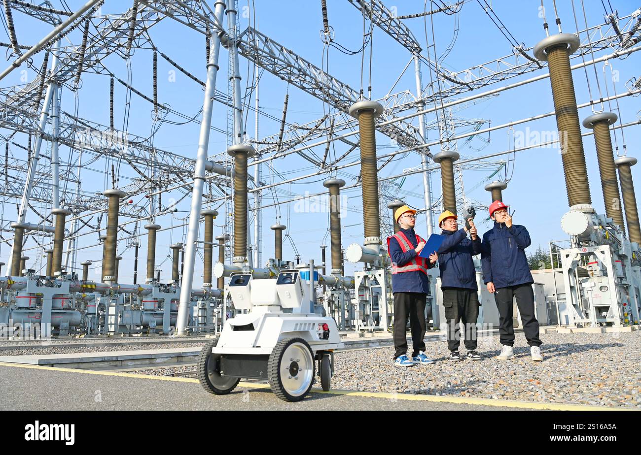 CHUZHOU, CHINE - 1er JANVIER 2025 - Un robot intelligent 5G et du personnel d'exploitation et de maintenance inspectent l'équipement d'alimentation principal en 50 Banque D'Images
