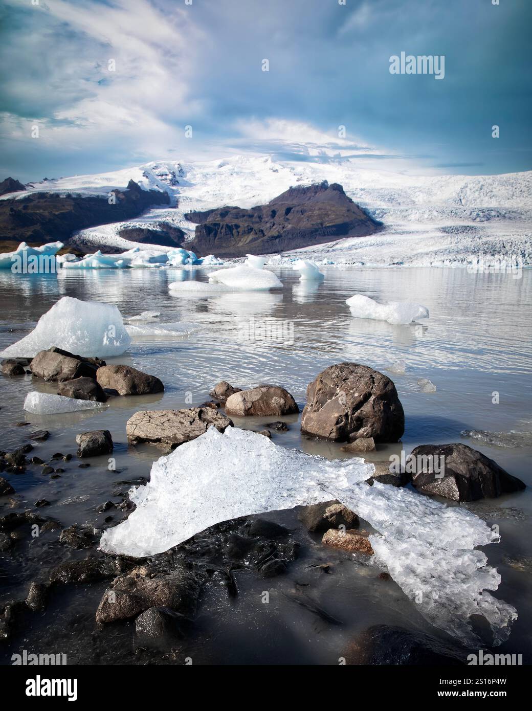 Le majestueux glacier de Fjallsjökull descend en cascade un flanc de montagne accidenté des hautes terres, son étendue glacée rencontrant les eaux sereines de Fjallsárlón gla Banque D'Images