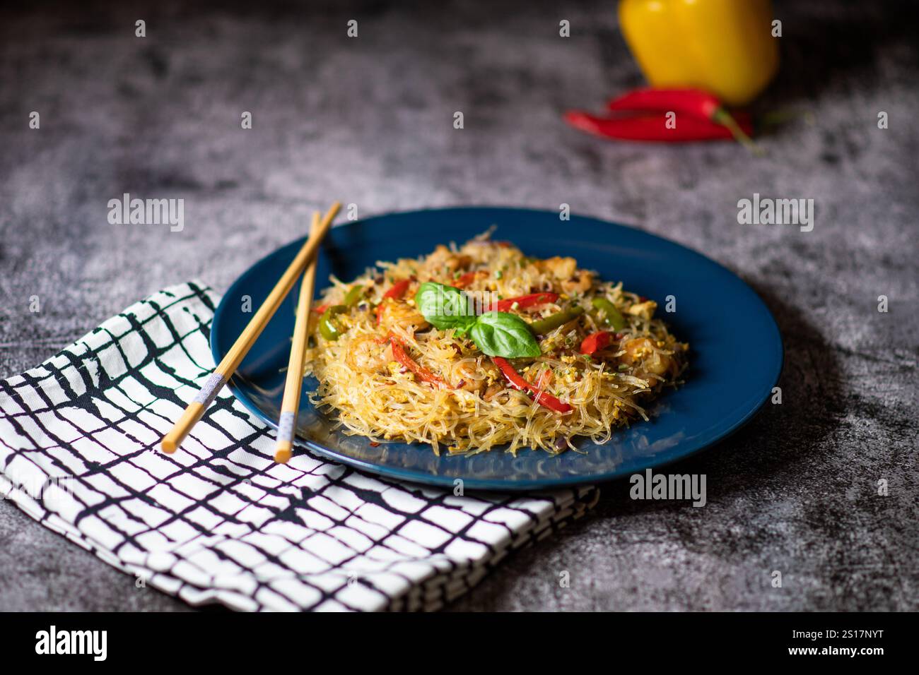 Salade asiatique avec nouilles en verre, poulet, crevettes, crevettes et légumes sur fond gris. Gros plan avec des baguettes. Focus sélectionné avec veget frais Banque D'Images