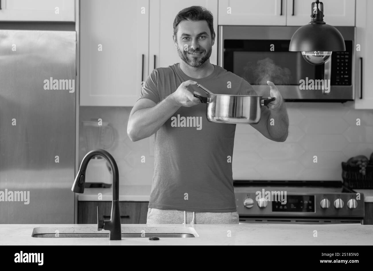 Cuisinier masculin ou chef cuisinant la nourriture dans la casserole dans la cuisine. Procédé de préparation d'un plat gastronomique. Homme cuisinant à la maison dans la cuisine, en utilisant la casserole. Chef cuisinant des aliments. Banque D'Images