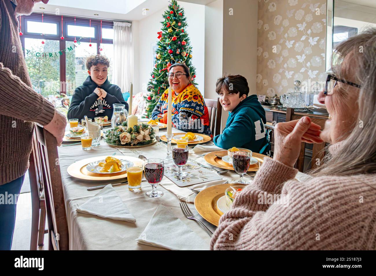 Une famille s'assoit ensemble et savoure un dîner de Noël rôti. Banque D'Images