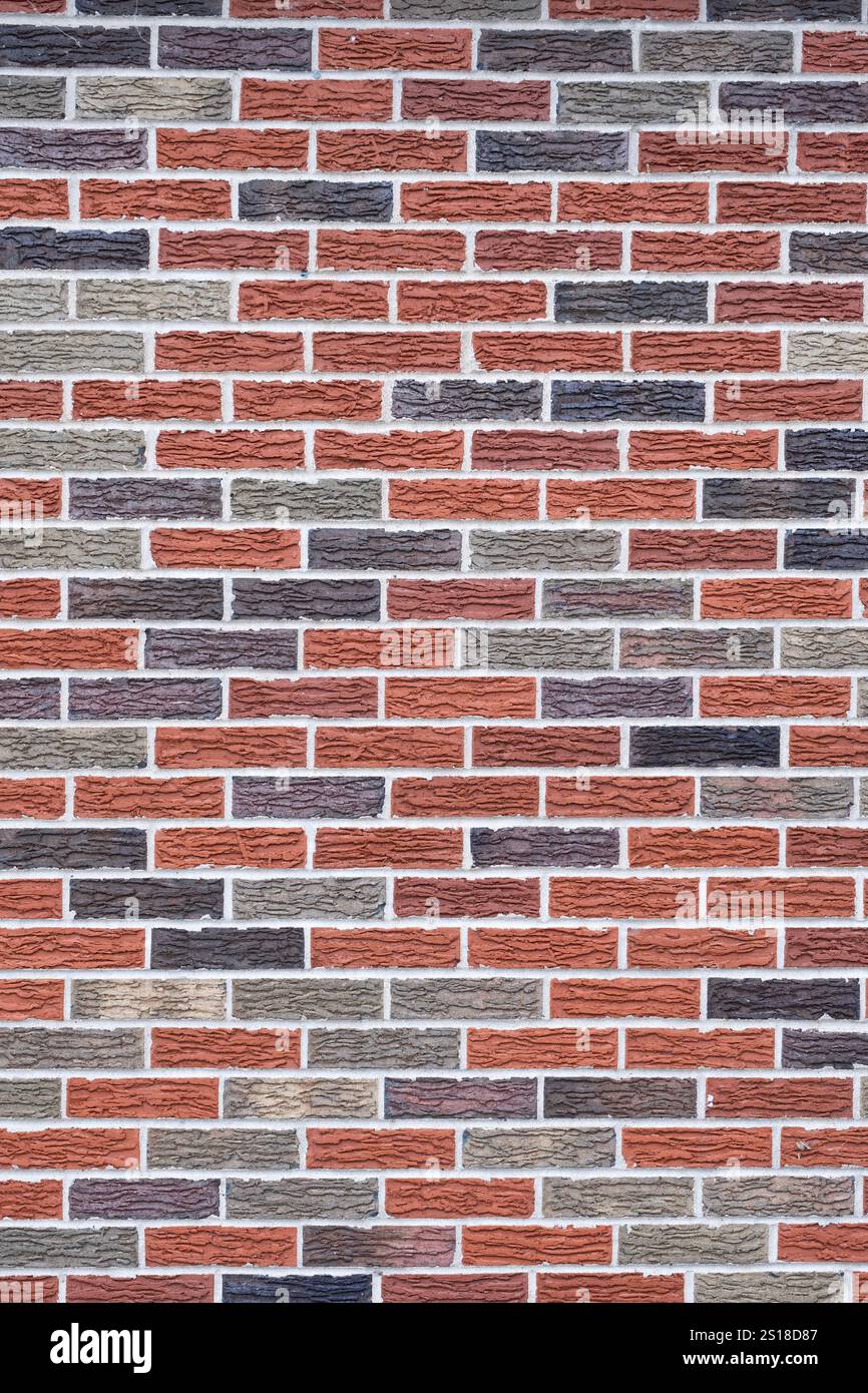 Arrangement d'un motif aléatoire de briques grises, noires et rouges avec mortier sur une surface de mur Banque D'Images