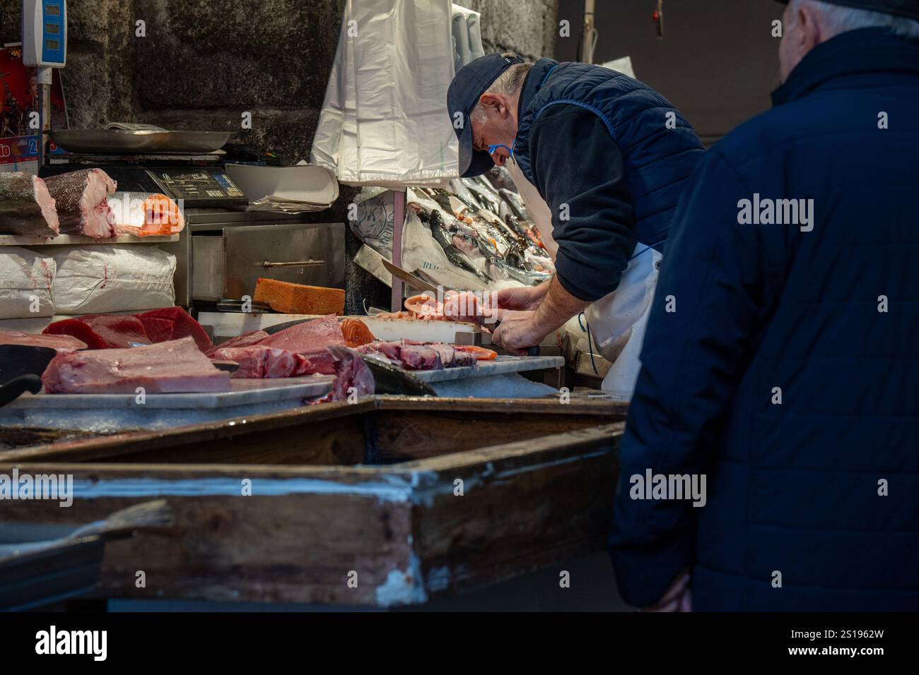 Catane, Italie - 30 décembre 2024 : un poissonnier prépare habilement des coupes de poisson frais sur le marché aux poissons emblématique de Catane, en Sicile. Une scène vibrante Banque D'Images