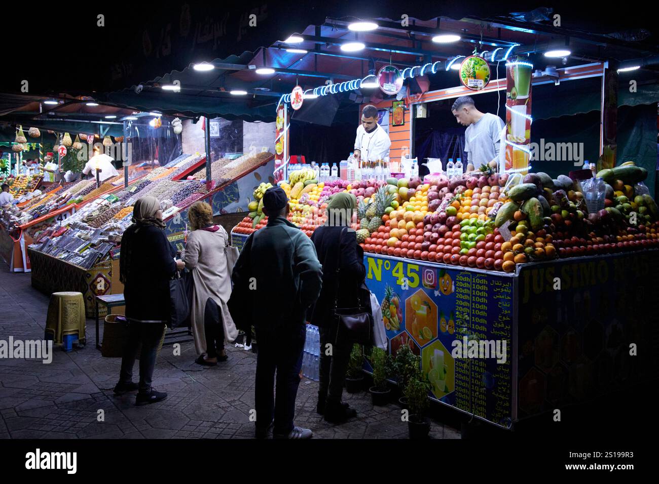 les habitants achètent des jus de fruits frais la nuit à un étal de la place jemaa el-fna marrakech, maroc Banque D'Images
