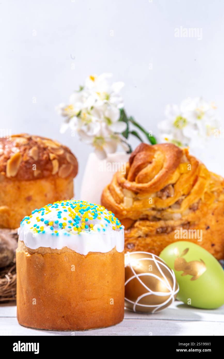 Fond de cuisson de Pâques avec des gâteaux de vacances traditionnels - kraffin, panettone, paska kulich, avec des œufs de Pâques, fleurs de printemps sur une table en bois blanc, sp Banque D'Images