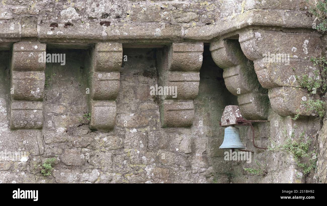 141 Mont-Saint-Michel, petite cloche rouillée entre les corbeaux d'un mur de parapet, rempart sur le versant nord au pied du réfectoire. Normandie-France. Banque D'Images