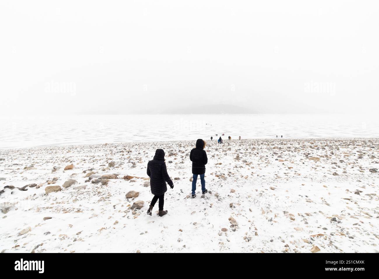 Vue du paysage du lac Abraham gelé brumeux en Alberta, Canada avec des visiteurs marchant sur la surface glacée éclipsée par le vaste paysage hivernal Banque D'Images Vue du paysage du lac Abraham gelé brumeux en Alberta, Canada avec des visiteurs marchant sur la surface glacée éclipsée par le vaste paysage hivernal Banque D'Images