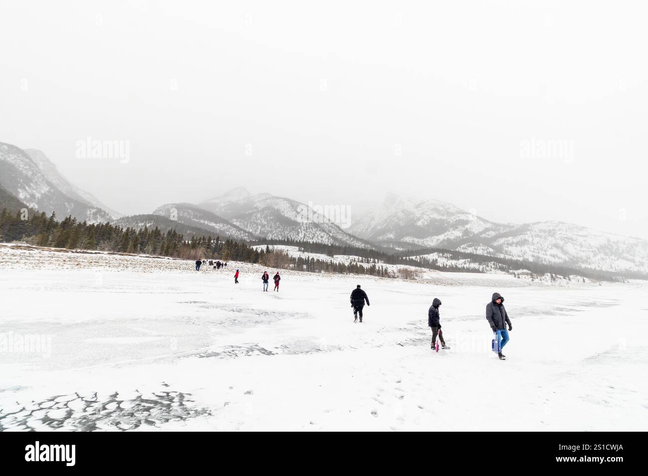 Vue du paysage du lac Abraham gelé brumeux en Alberta, Canada avec des visiteurs marchant sur la surface glacée éclipsée par le vaste paysage hivernal Banque D'Images Vue du paysage du lac Abraham gelé brumeux en Alberta, Canada avec des visiteurs marchant sur la surface glacée éclipsée par le vaste paysage hivernal Banque D'Images