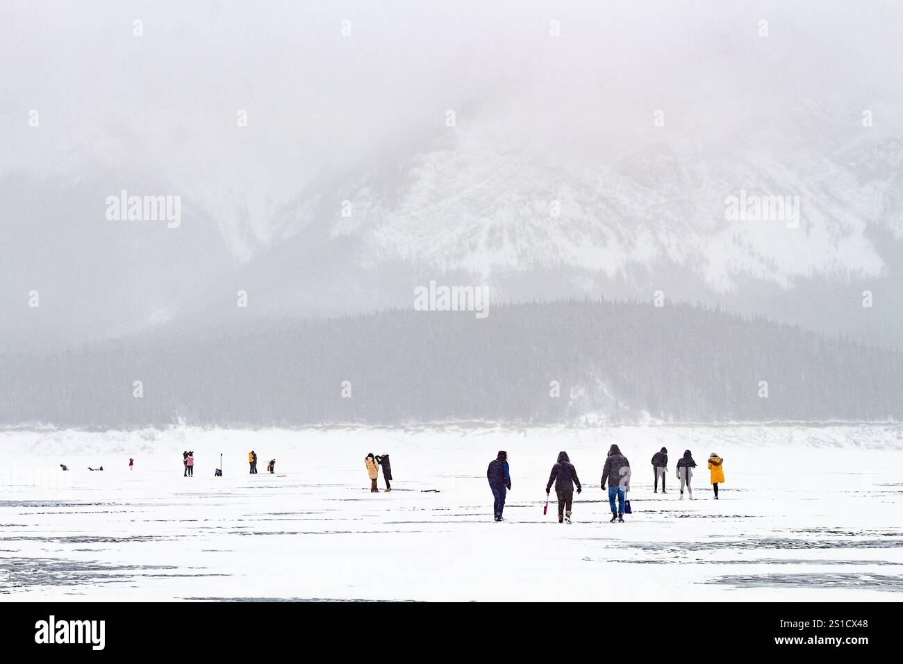 Vue du paysage du lac Abraham gelé brumeux en Alberta, Canada avec des visiteurs marchant sur la surface glacée éclipsée par le vaste paysage hivernal Banque D'Images Vue du paysage du lac Abraham gelé brumeux en Alberta, Canada avec des visiteurs marchant sur la surface glacée éclipsée par le vaste paysage hivernal Banque D'Images