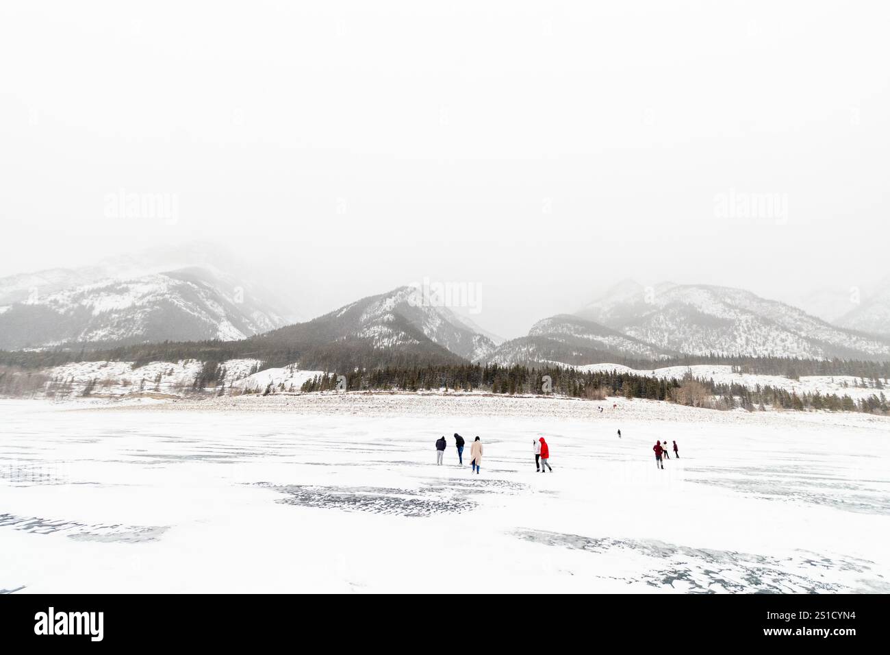 Vue du paysage du lac Abraham gelé brumeux en Alberta, Canada avec des visiteurs marchant sur la surface glacée éclipsée par le vaste paysage hivernal Banque D'Images Vue du paysage du lac Abraham gelé brumeux en Alberta, Canada avec des visiteurs marchant sur la surface glacée éclipsée par le vaste paysage hivernal Banque D'Images