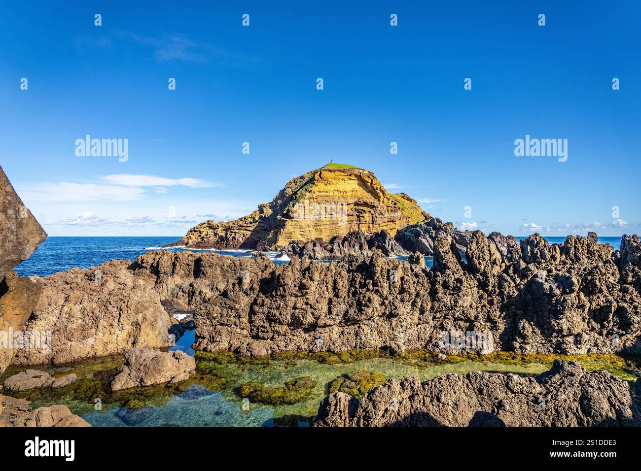 Découvrez la tranquillité de ce paysage côtier accidenté avec une piscine naturelle et une vue panoramique sur l'océan, entouré d'impressionnantes formations rocheuses Banque D'Images