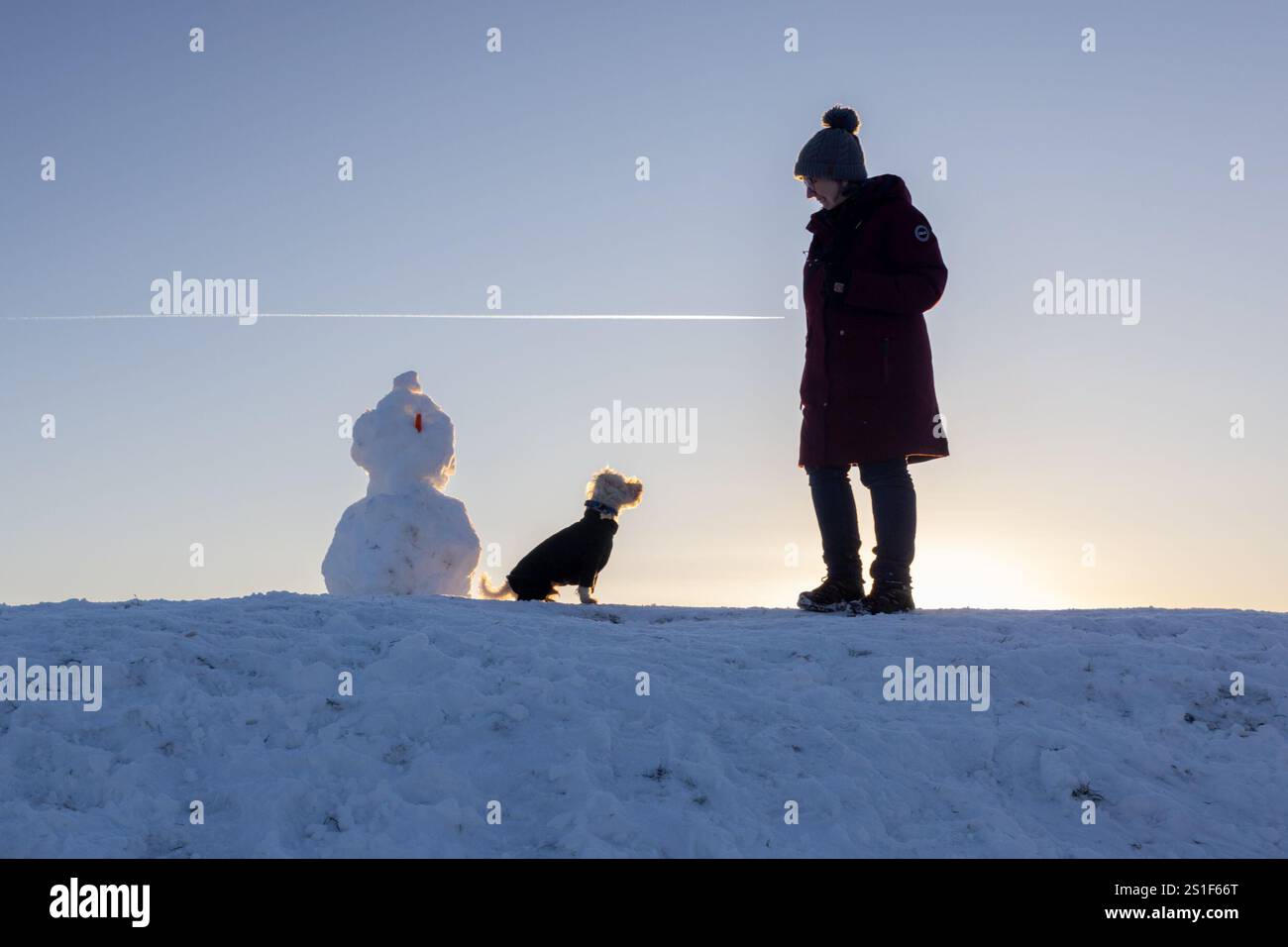 Harlaw. Balerno. Midlothian. Écosse, Royaume-Uni. 3 janvier 2025. Monty le Schoodle est plus intéressé par un biscuit de maman Andrea que par la carotte sur le bonhomme de neige pendant leur promenade dans des conditions de gel au réservoir Harlaw près de Balerno dans le Midlothian (crédit photo : David Mollison/Alamy Live News Banque D'Images
