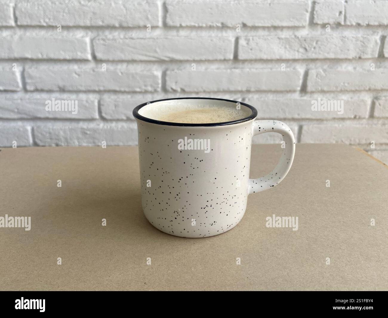 Tasse en céramique blanche rustique avec design moucheté sur une surface neutre Banque D'Images