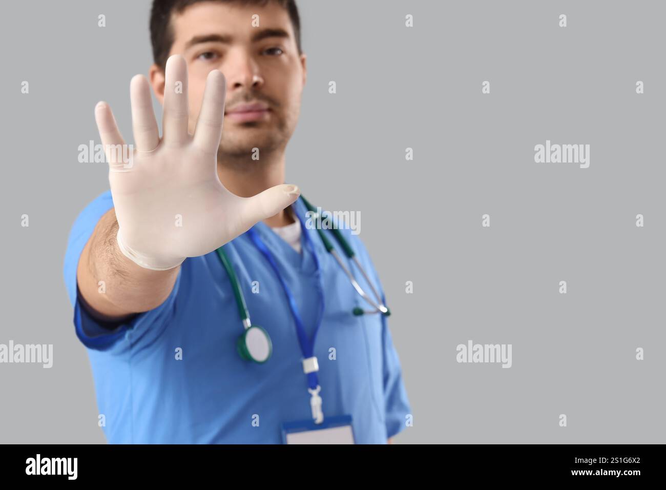 Médecin masculin montrant un geste D'ARRÊT sur fond gris Banque D'Images