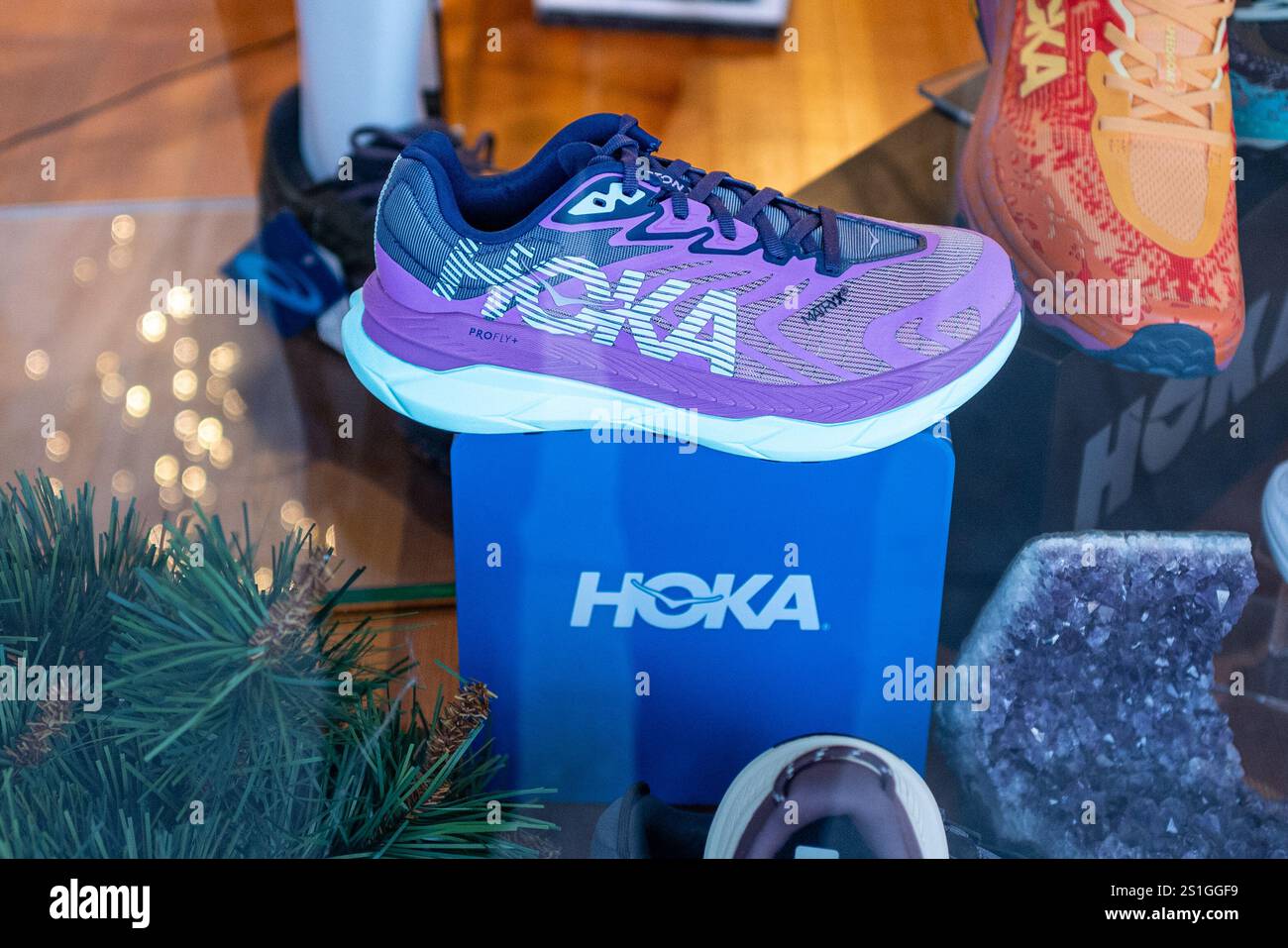 Gros plan photo d'une chaussure violette Hoka dans une vitrine d'un magasin de chaussures. Les chaussures Hoka ont pris d'assaut le monde de la course à pied ces dernières années. Banque D'Images