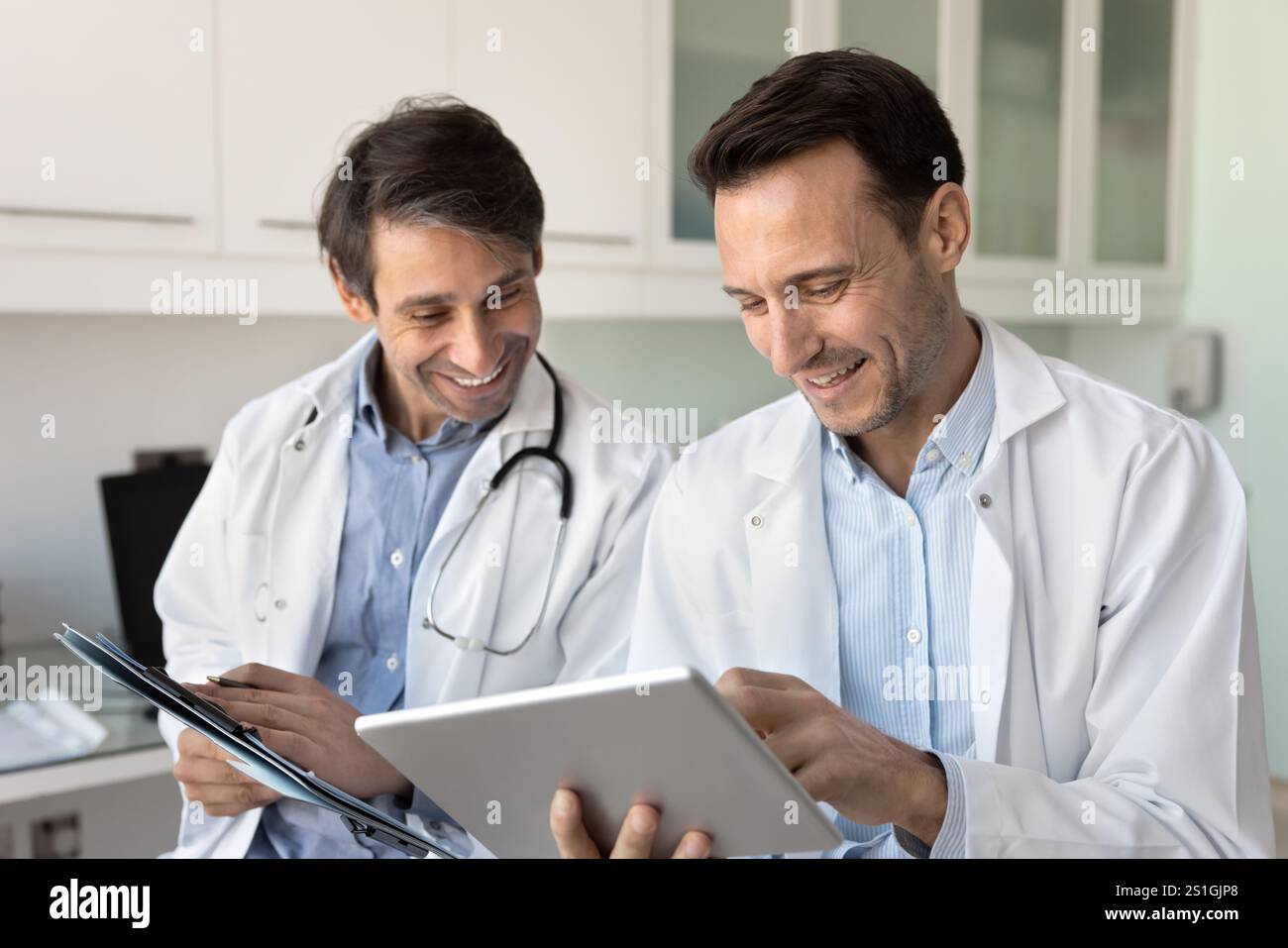Deux docteurs masculins positifs travaillant ensemble sur des rapports médicaux Banque D'Images