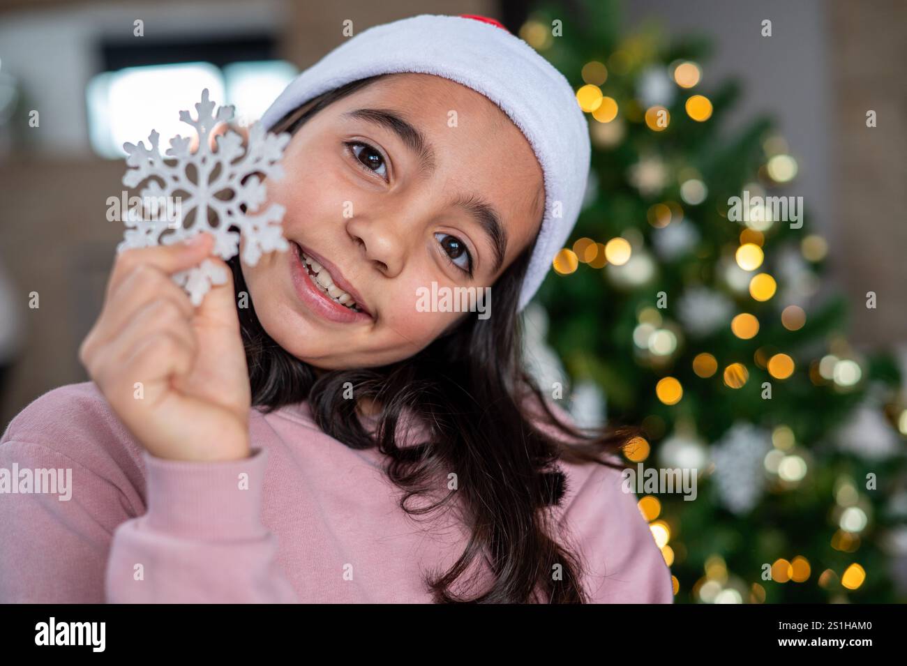 Une jeune fille tient un flocon de neige dans sa main et sourit. Concept de joie et d'excitation, car la fille célèbre probablement la saison des fêtes. Le Banque D'Images