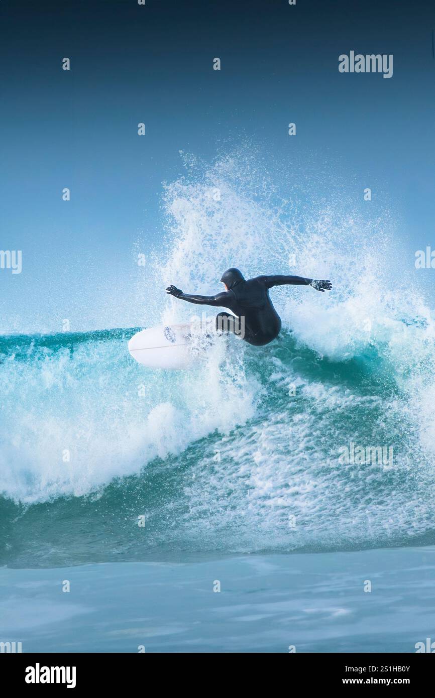 Un surfeur qui fait une vague à Fistral à Newquay, en Cornouailles, au Royaume-Uni. Banque D'Images