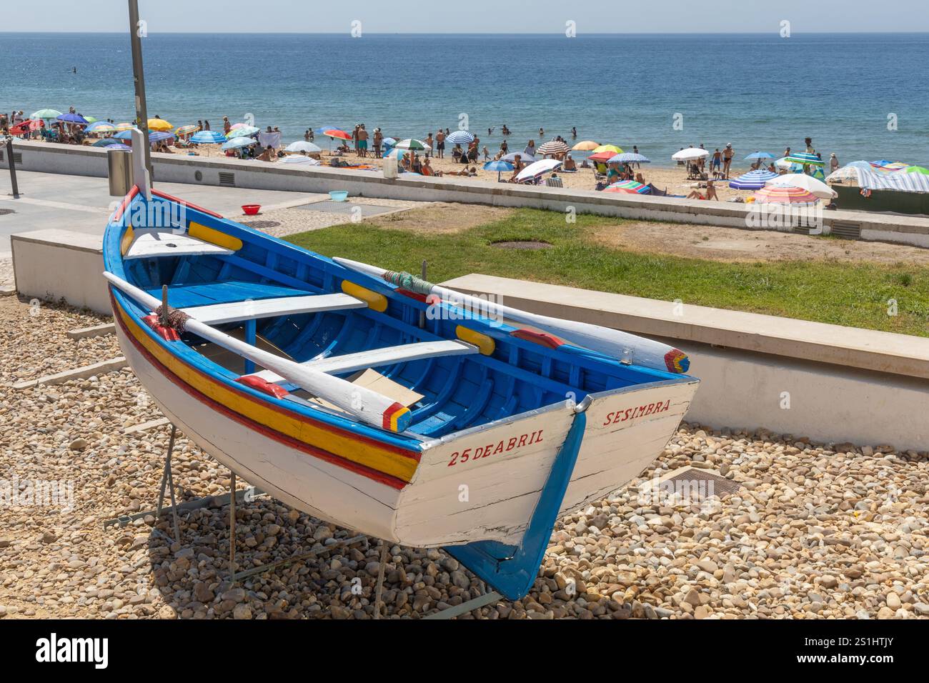 Sesimbra, Portugal. 8 août 2024. Bateau de pêche traditionnel et coloré sur la côte de l'océan Atlantique avec une plage pleine de gens. Sesimbra Portu Banque D'Images