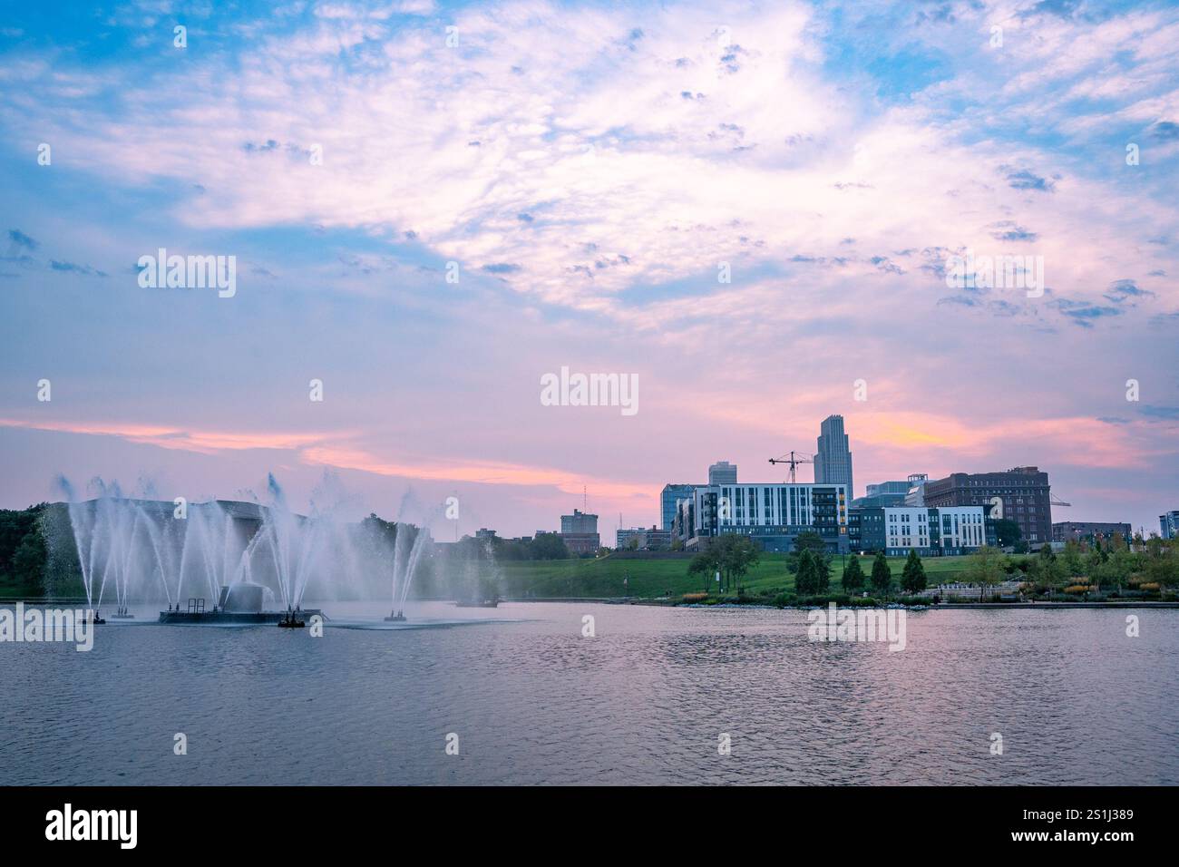 Vue de l'horizon d'Omaha Nebraska au coucher du soleil vu depuis Heartland of America Riverside Park avec le lac en vue. Banque D'Images