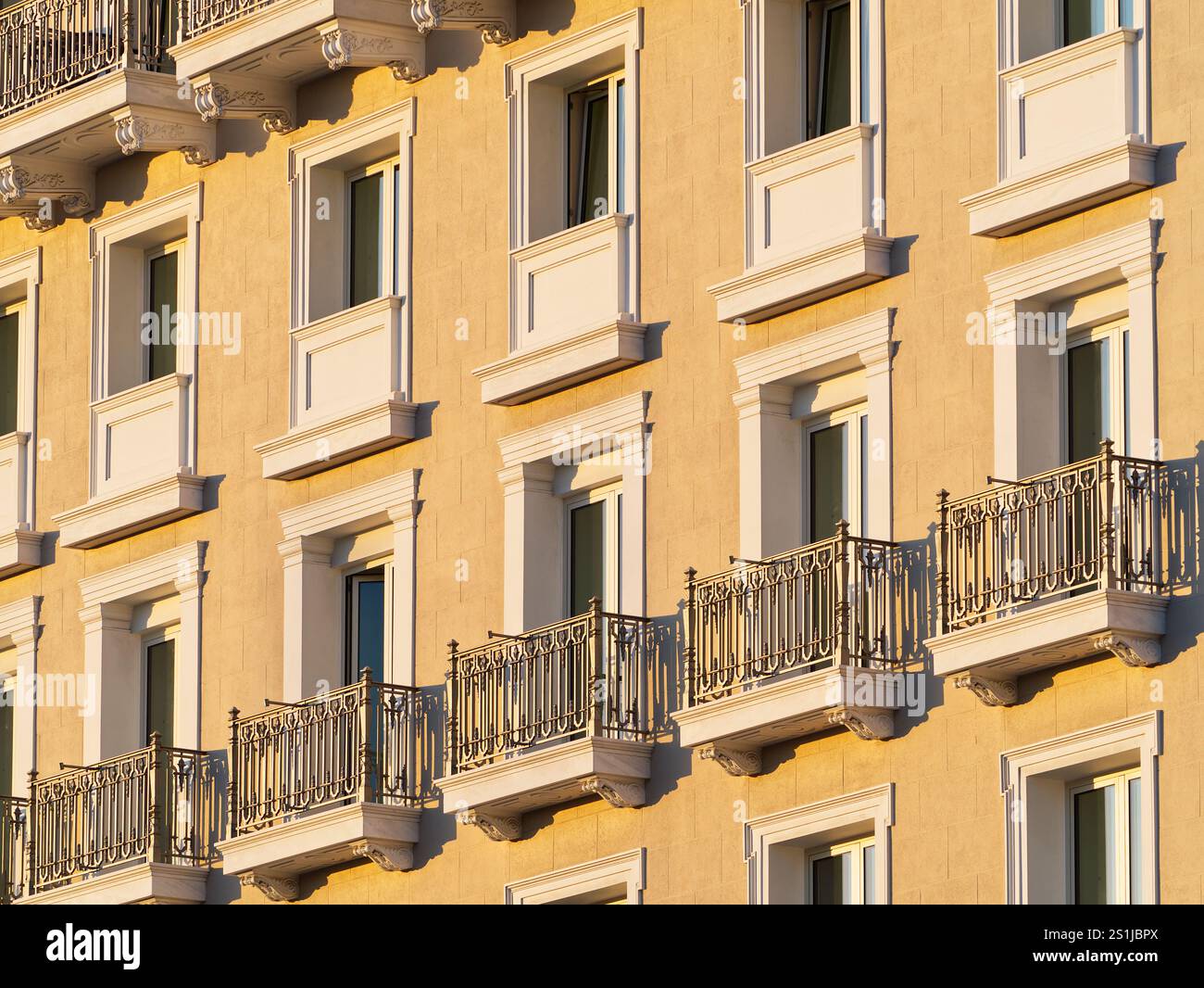Façade d'un immeuble jaune avec balcons décoratifs en fer forgé et fenêtres blanches Banque D'Images