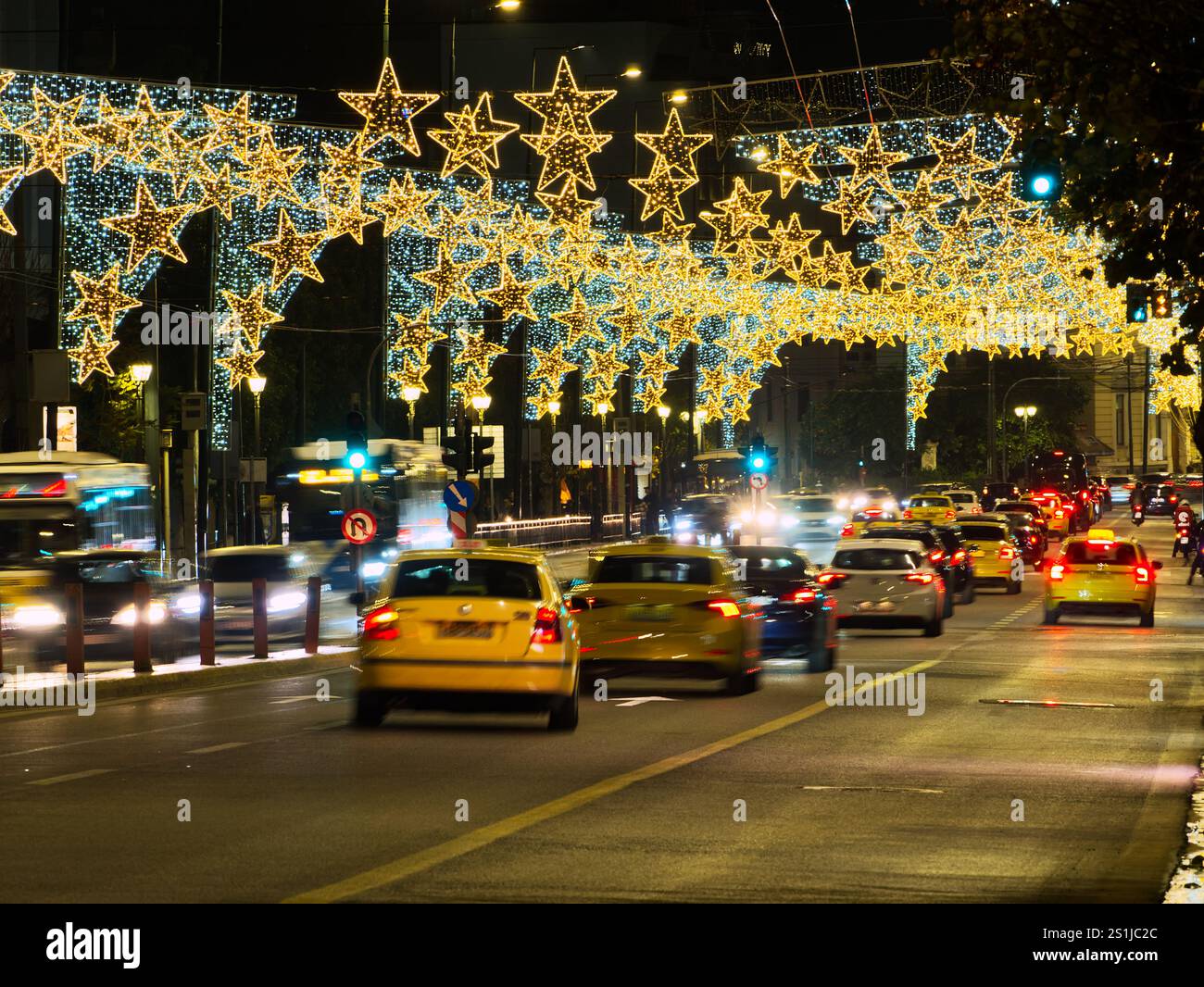 Athènes, Grèce - 3 janvier 2025 : rue urbaine animée la nuit avec circulation floue et décorations lumineuses de Noël élaborées en forme d'étoile Banque D'Images
